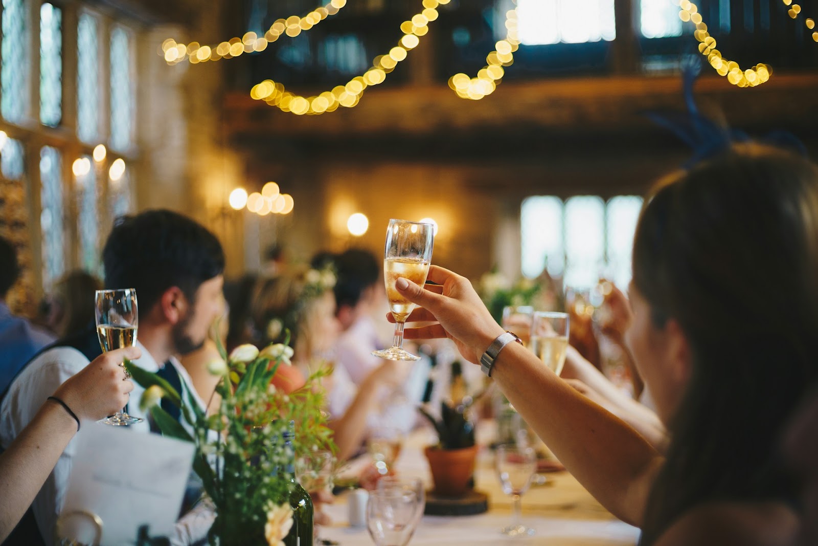 People raising their glasses for the toast during a wedding speech. 