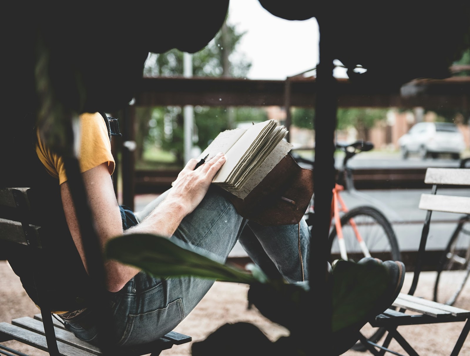 A person sitting outside, writing in their book journal ideas.