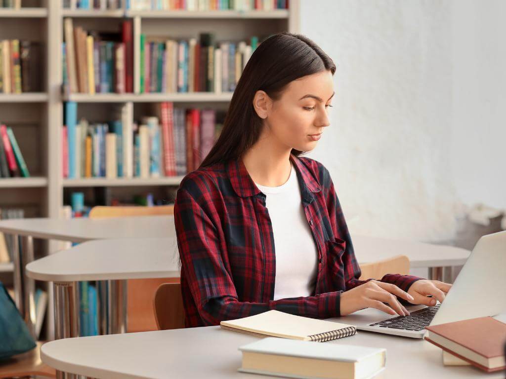 a girl student is typing her book review on the computer