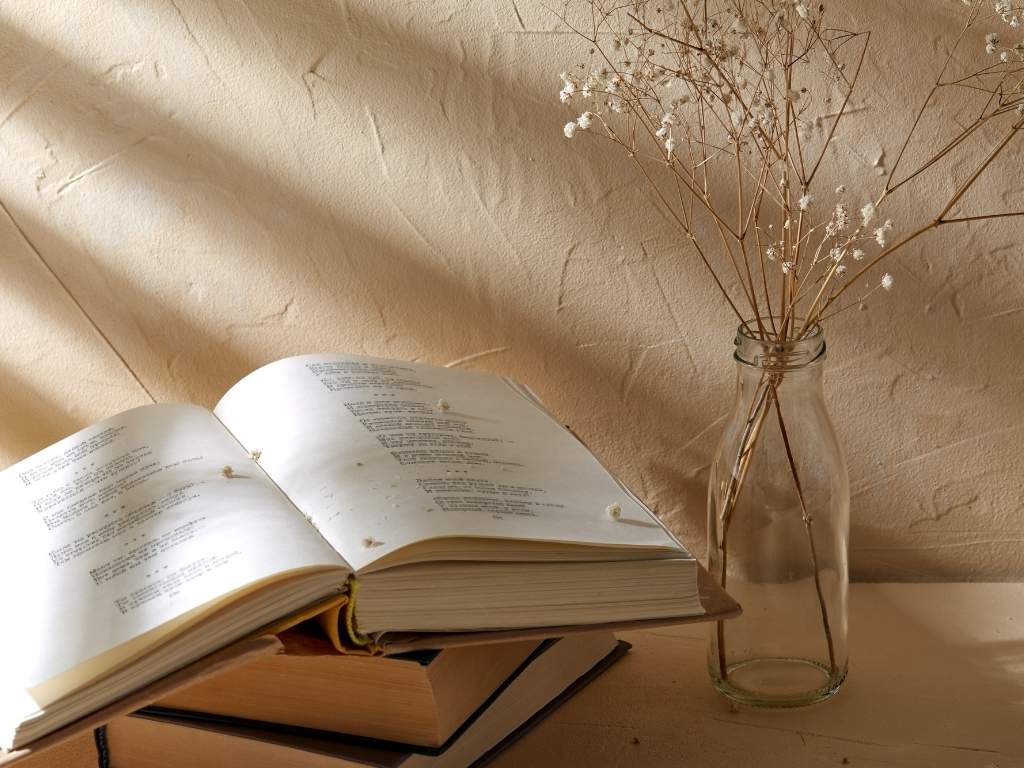 a poetry book placed near a vase containing beautiful flowers