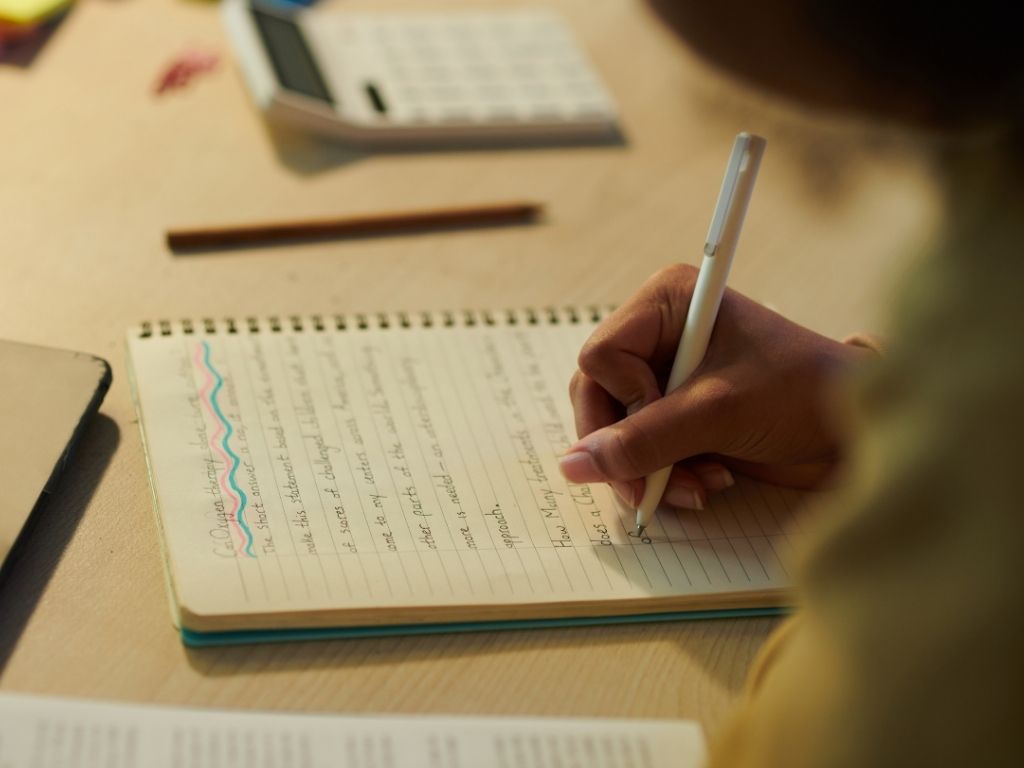 a girl writing a persuasive essay outline on her notebook