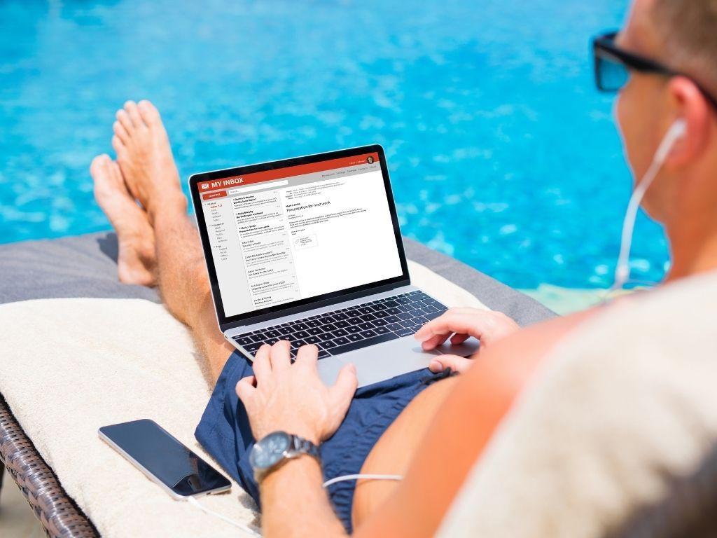 A man sitting on a chair by the pool, working on his laptop in a relaxed setting. How To Create A Folder In Gmail?