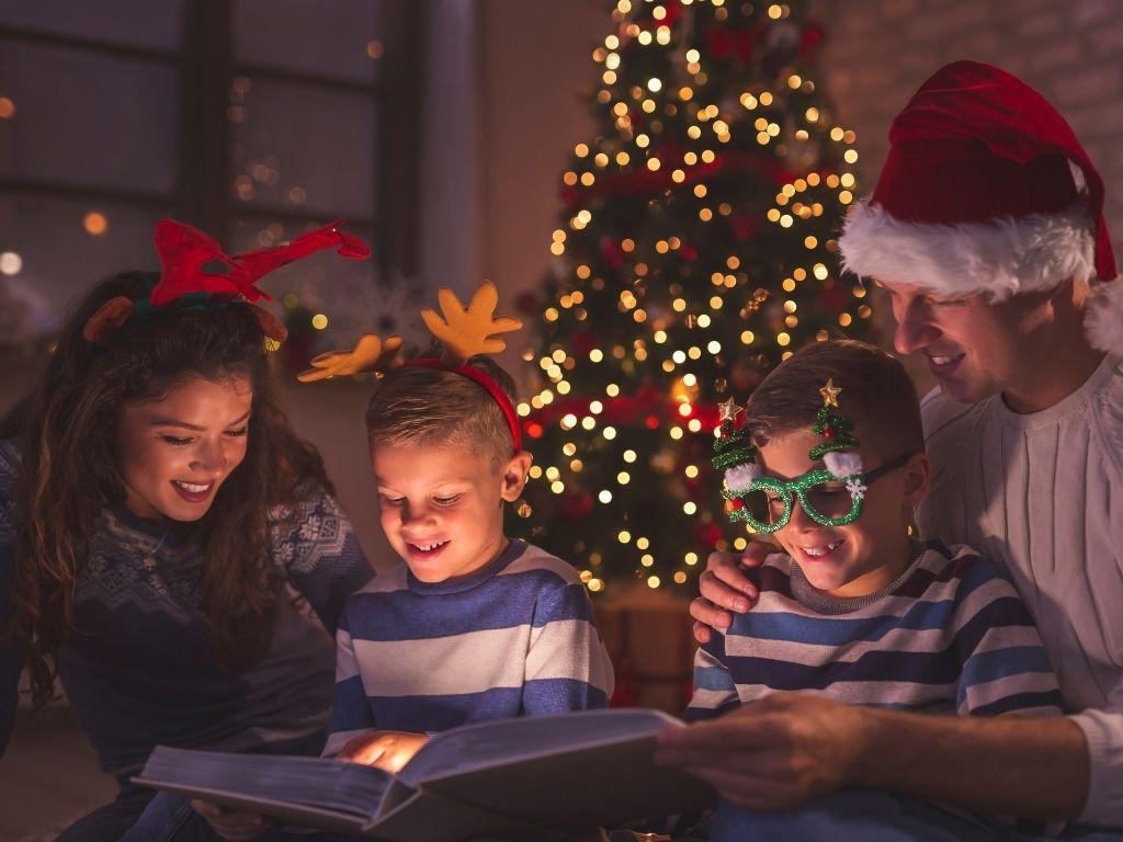 kids enjoying reading a book with their parents on Christmas