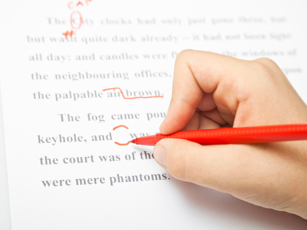 a person writing with red pen on a book