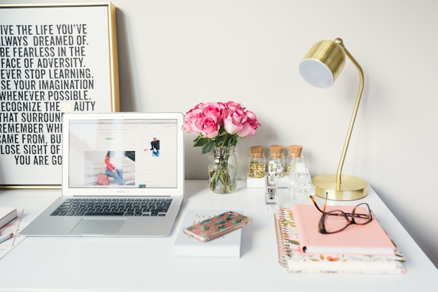 A white desk with a computer, lamp and book