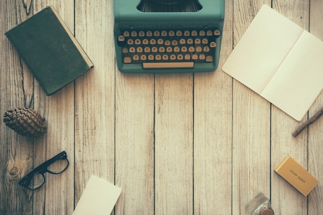 A wooden desk with a type writer and writing instruments