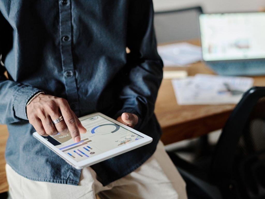 A man reviewing analytics on his tablet, propped at an angle on his table.