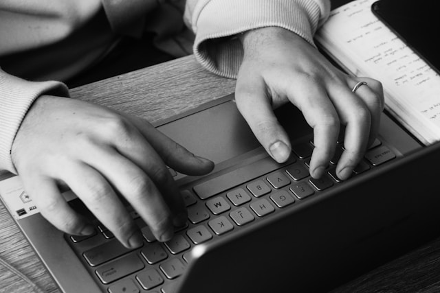 A person typing on a laptop grey scale