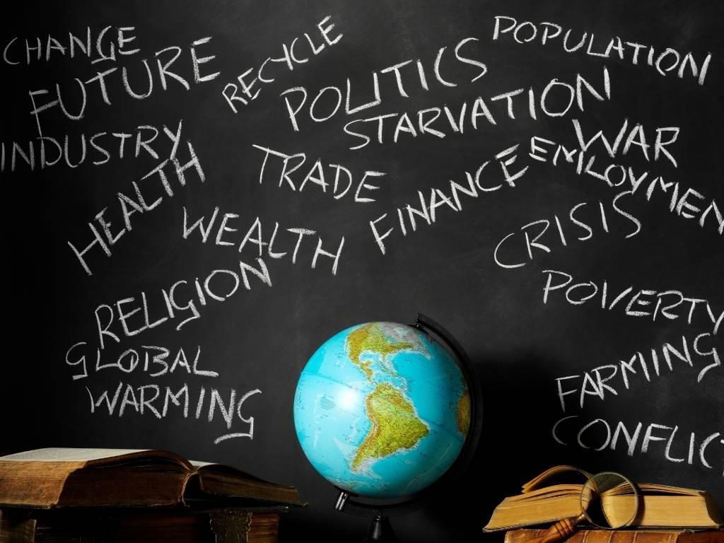 a globe placed on a table with a blackboard behind it displaying different words.