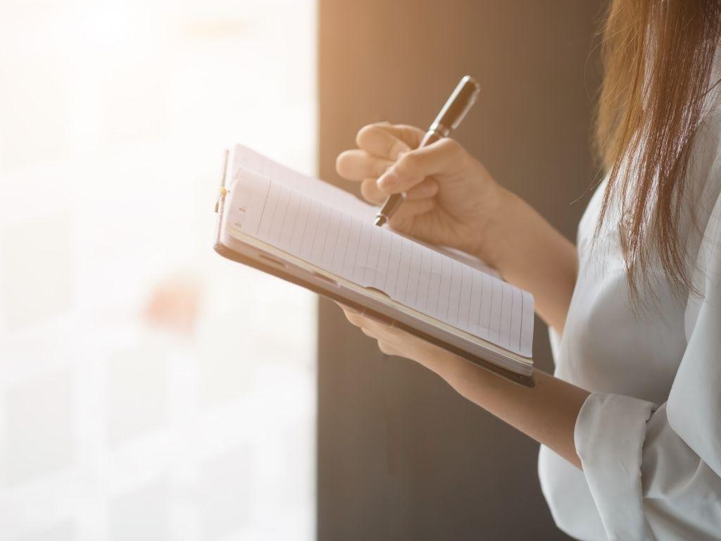 a girl writing on her notebook with a black pen