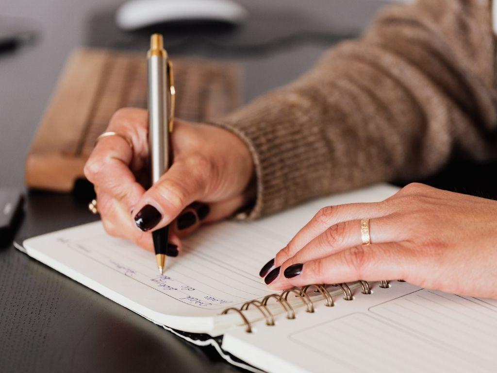 A girl writing an analytical essay on her notebook with a ball pen.