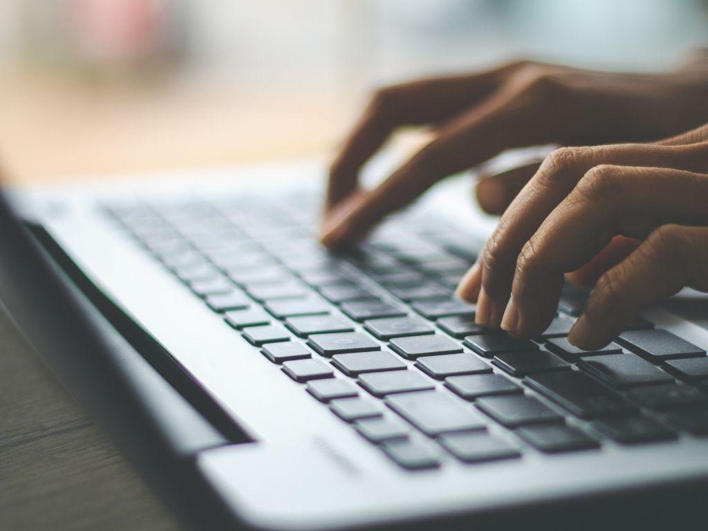 a man working on a laptop trying to find on How To Write a Book Title in an Essay