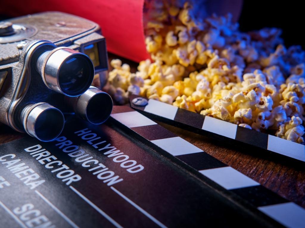 A camera, popcorn, and a "Roll Camera" clapperboard placed nearby.