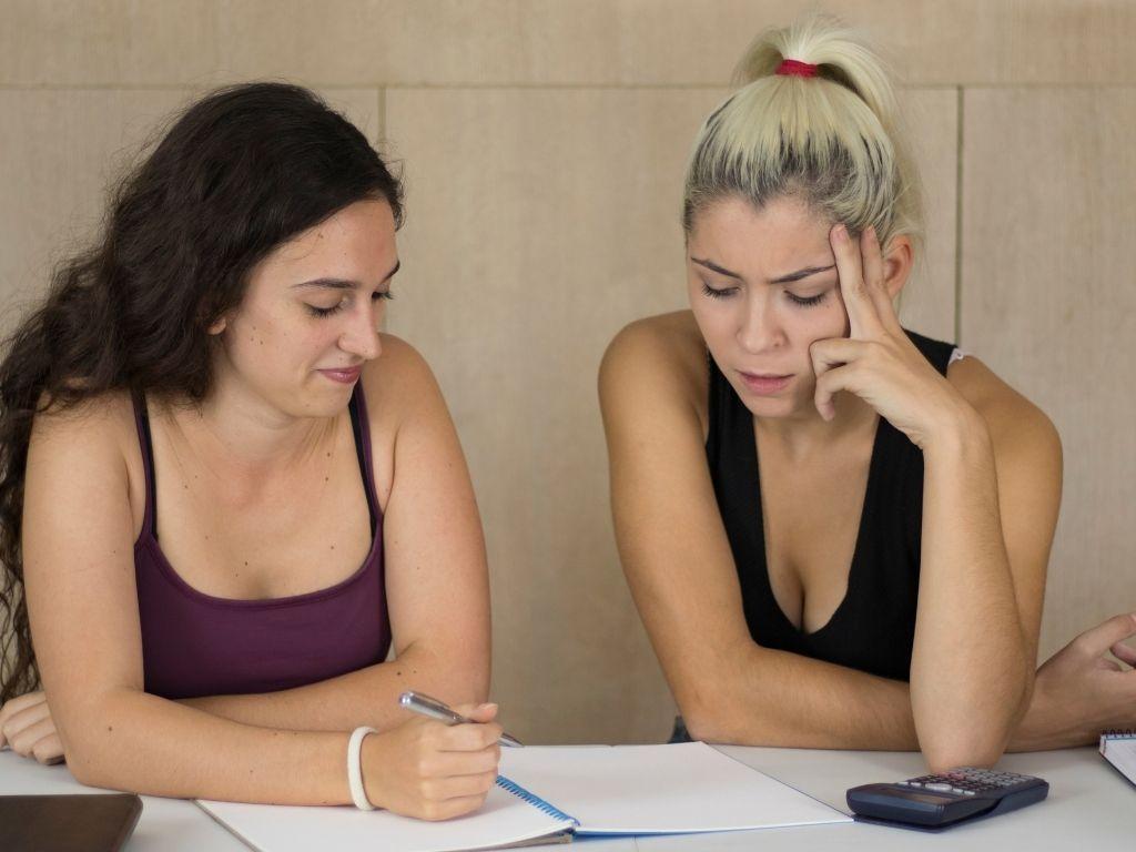 Two girls working on a notebook and thinking How To Cite An Essay