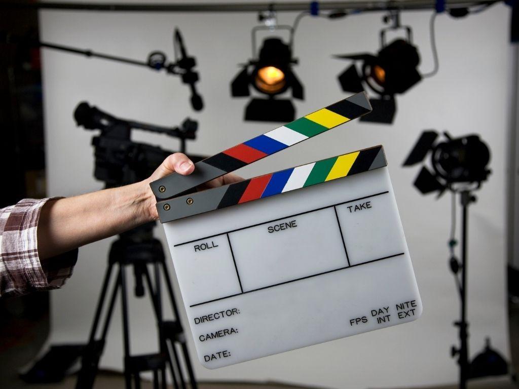 A man holding a "Scene Take" clapperboard, ready for a film shot.