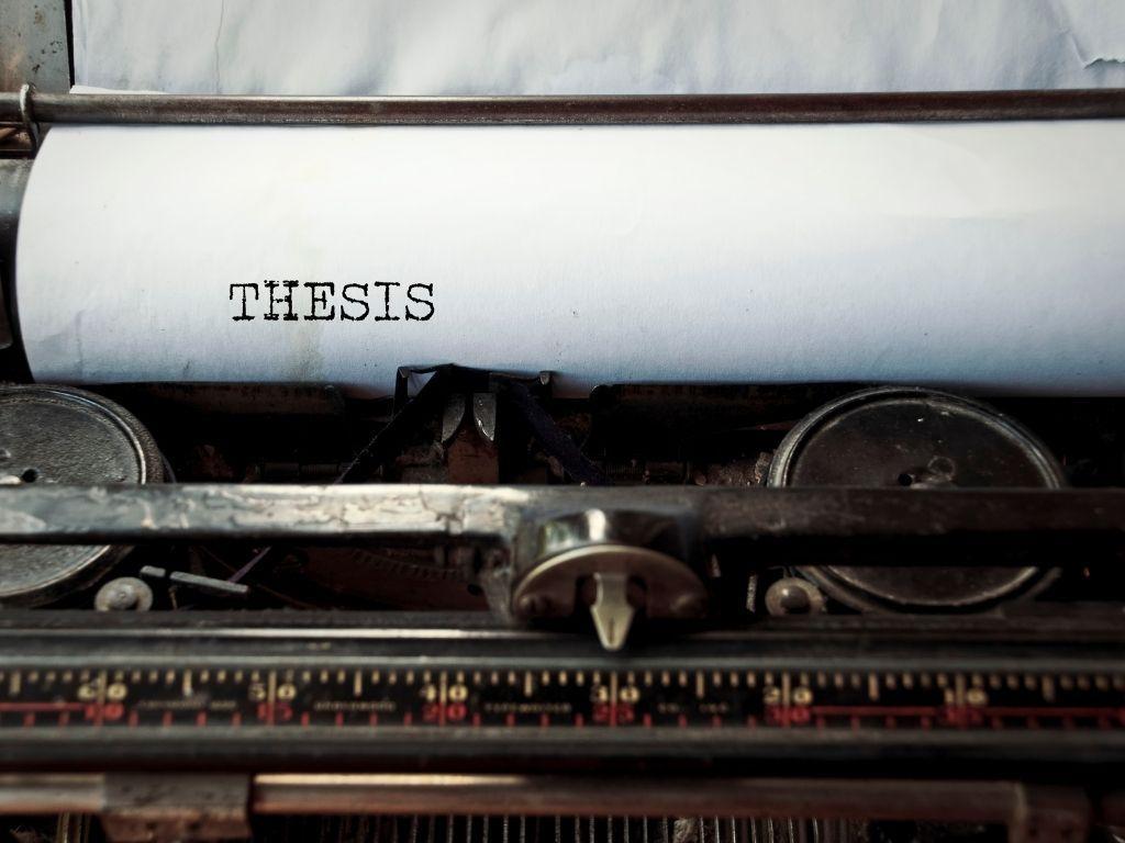 A vintage typewriter with a sheet of paper emerging, the word "Thesis" typed prominently on it.