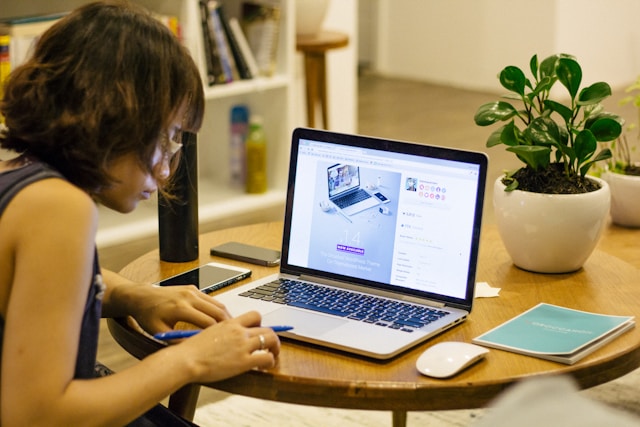 A student with a laptop and a plant on the table