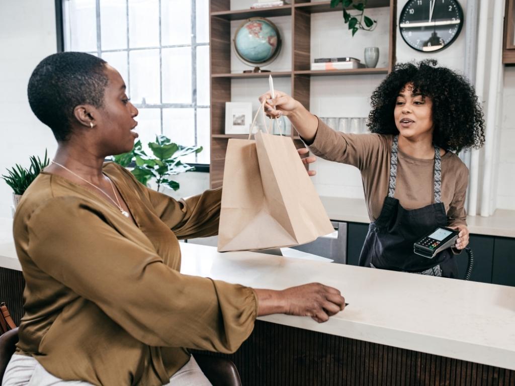 Two individuals engaged in a transaction, with one person handing over a bag to the other, symbolizing the exchange of goods.