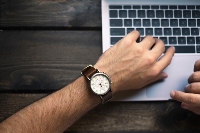 a person with a watch typing on a computer