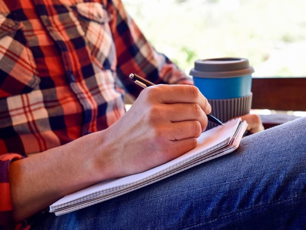 a man writing on a notebook.