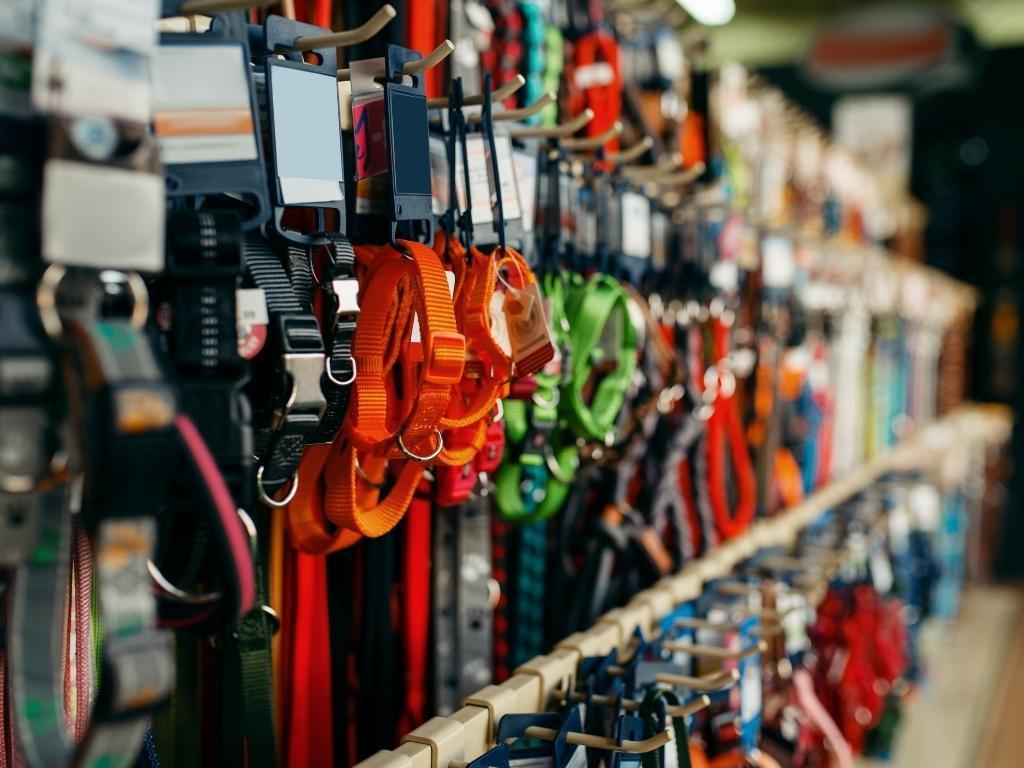 A variety of dog leashes neatly displayed in a pet shop, hanging on hooks in different colors, materials, and styles. Some leashes are retractable, while others are made of sturdy nylon or leather. The arrangement showcases options for different dog sizes and walking preferences, creating an inviting shopping experience for pet owners.