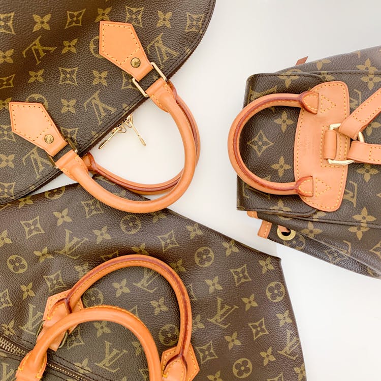 Free High-end designer leather handbags with monogram pattern lay elegantly displayed. Stock Photo