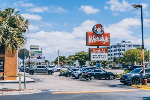 Free Wendy's parking area crowded with cars under a clear blue sky in Orlando. Stock Photo