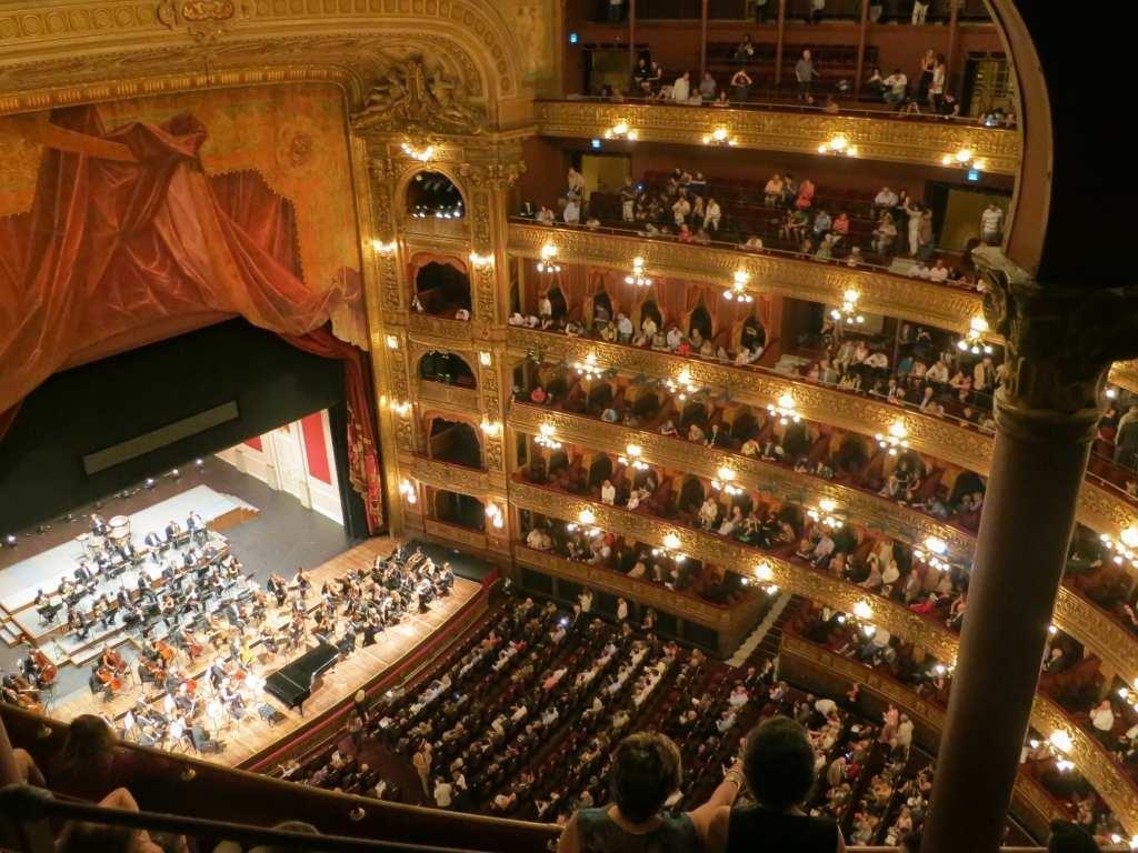 Performers bring a story to life on stage as the audience watches in awe in a grand theater setting